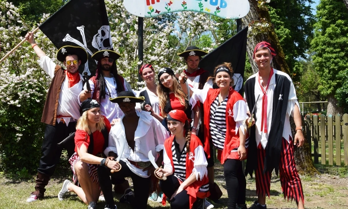 Group of people dressed as pirates posing together outside in front of "miniClub" sign; surrounded by trees at Union Lido