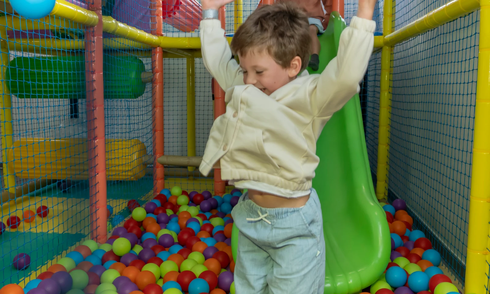 Children playing in an indoor ball pit area; one child slides while another joyfully raises arms amidst colorful balls at Ohai Nazaré Outdoor Resort