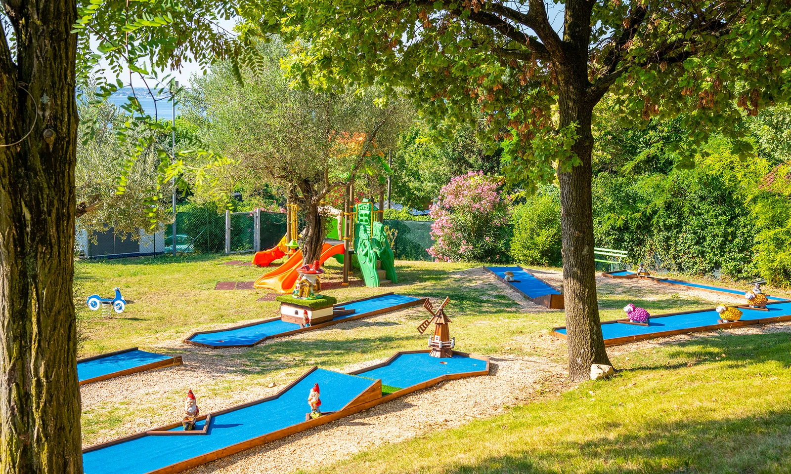 Mini-golf course with whimsical decorations in a leafy, shaded playground at Fontanelle