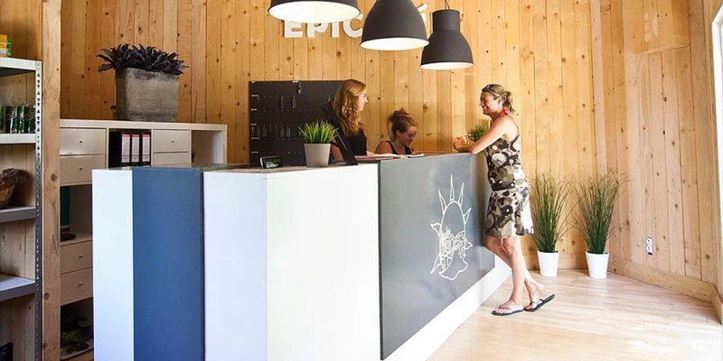 Reception desk with two staff assisting a guest, set in a wood-paneled office at Slow Village Provence Occitane 