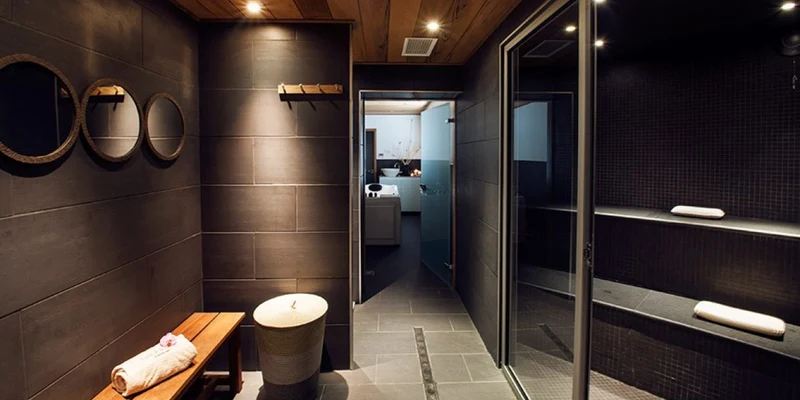 A modern sauna with bench seating, tiled walls, and towels, adjacent to a changing room at Holiday Marina Resort