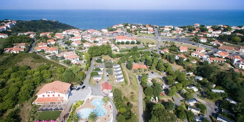 Aerial view of a coastal town featuring houses, roads, and greenery, with the sea in the background at Erreka