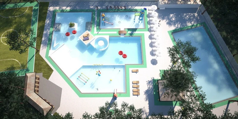 Outdoor swimming pools with slides and lounging chairs, adjacent to a soccer field surrounded by trees at Mare E Pineta