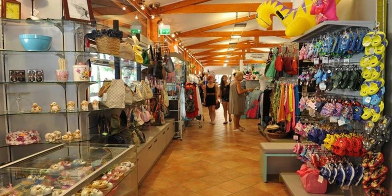 Store selling various beach goods with customers browsing the aisles, surrounded by colorful items and wooden beams overhead at Isamar