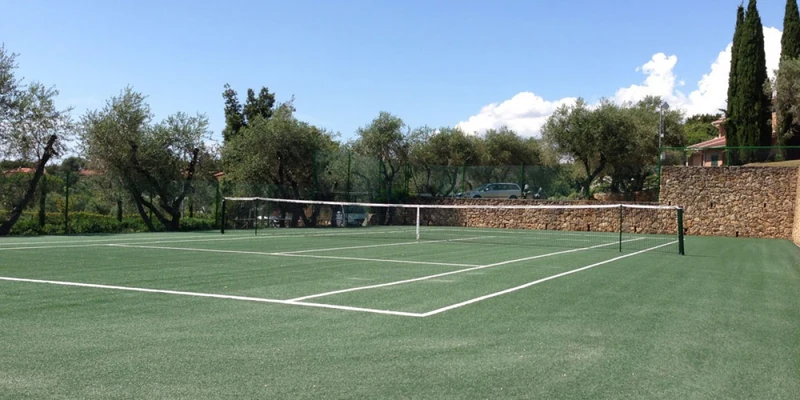 Tennis court standing unused, surrounded by trees and stone walls at Valle Gaia