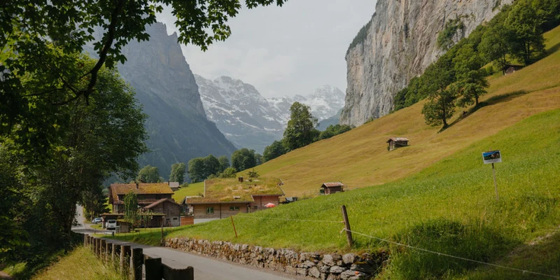Houses nestled in a lush valley with a road and towering mountains in the background at Jungfrau