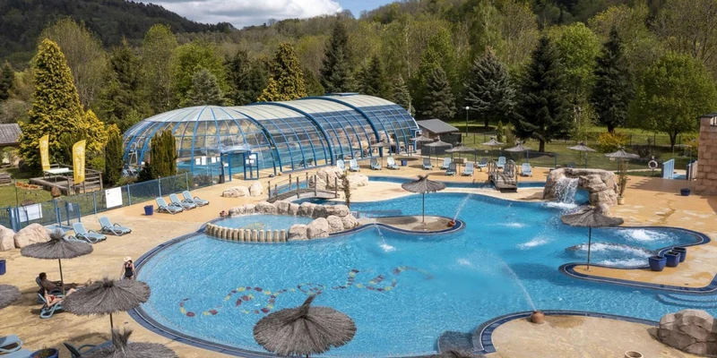 Outdoor pool with loungers, water features, surrounded by trees and hills at La Ribeyre