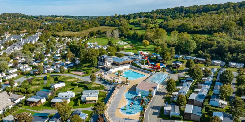 Water park with slides and pools surrounded by caravans, trees, and hills at Marvilla Parks La Vallée