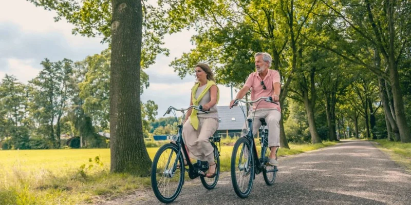 Two people riding bicycles on a tree-lined path in a rural area at Europarcs Reestervallei