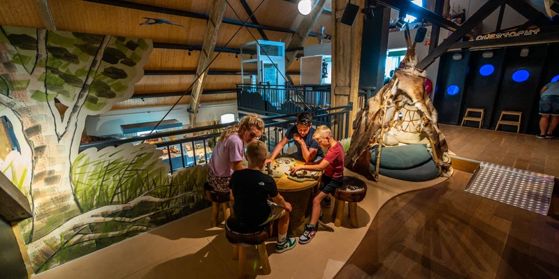 Children playing at a table in a colorful, wooden-themed indoor play area at Europarcs Poort van Zeeland