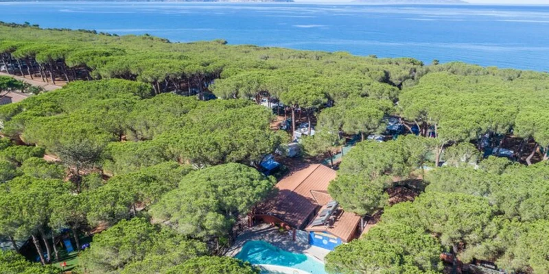 Dense forest surrounds buildings and a pool, situated near a calm coastline with distant islands in view at Il Gabbiano