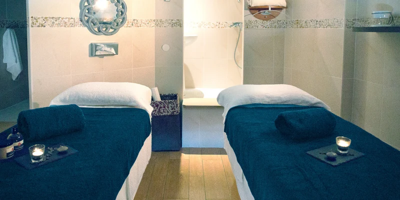 Two massage tables with rolled towels and lit candles, set in a warmly lit spa room at Les Bulles de Mer