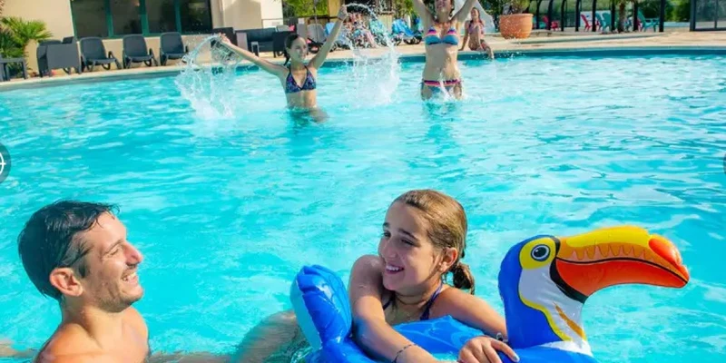 Children playing in a swimming pool, an adult man and a girl with a bird-shaped float at Marvilla Parks Pommeraie de l'Océan