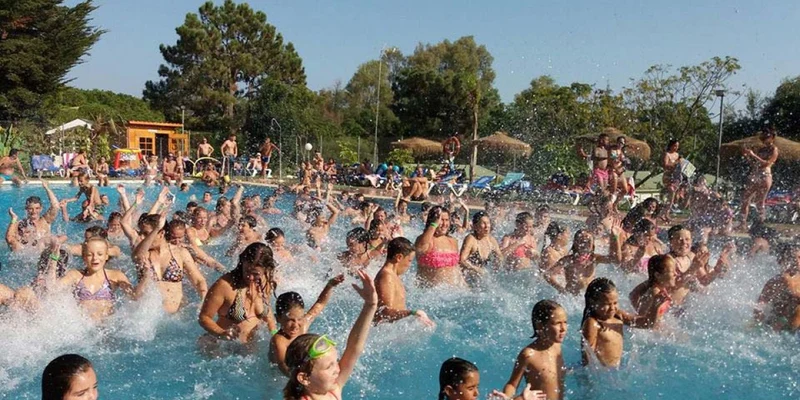 Many people splash water in a crowded outdoor pool at Cabopino