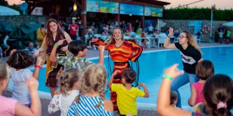Children dance with adults near a swimming pool at Residence Eden