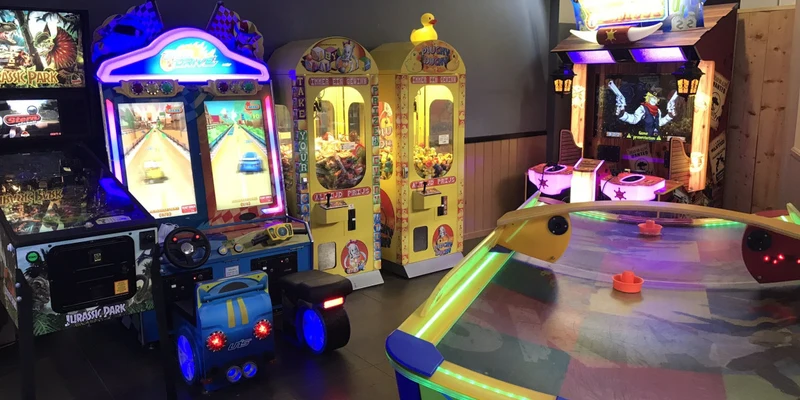 Arcade machines stand idle, glowing with neon lights, surrounded by colorful toys at Ferienresort Bad Bentheim