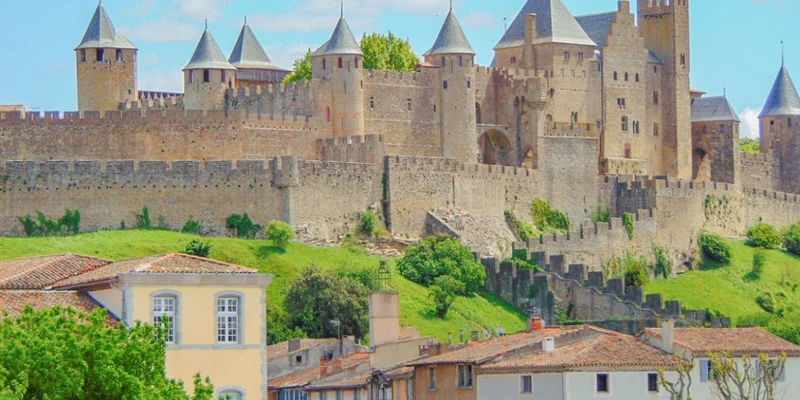 Castle with tall towers and fortifications overlooking village houses, surrounded by greenery at Paradis Barberousse