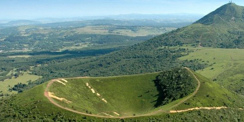Green dormant volcano with hiking trails, surrounded by lush valleys and rolling hills at Le Ranch des Volcans