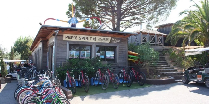 Bicycles parked outside a wooden rental shop, surrounded by trees and stairs leading up at Kon Tiki