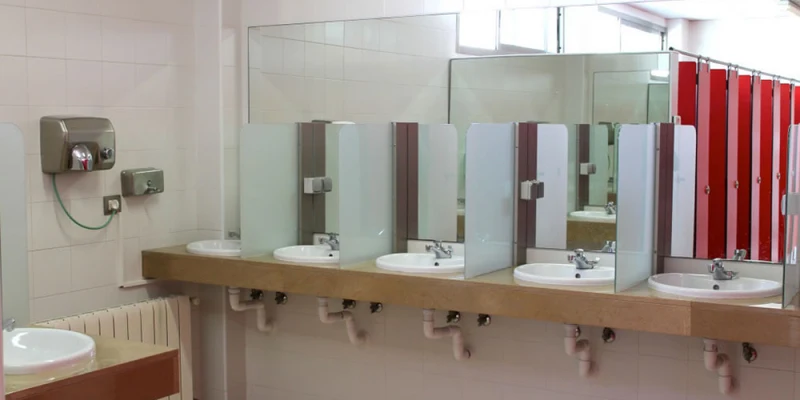 Sinks with mirrors and red stall doors inside a tiled communal bathroom at Almafra