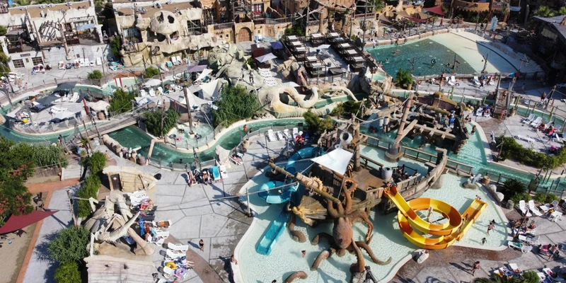 Aquatic play structures host people swimming and sunbathing in a crowded water park at Resort Cap Pirate