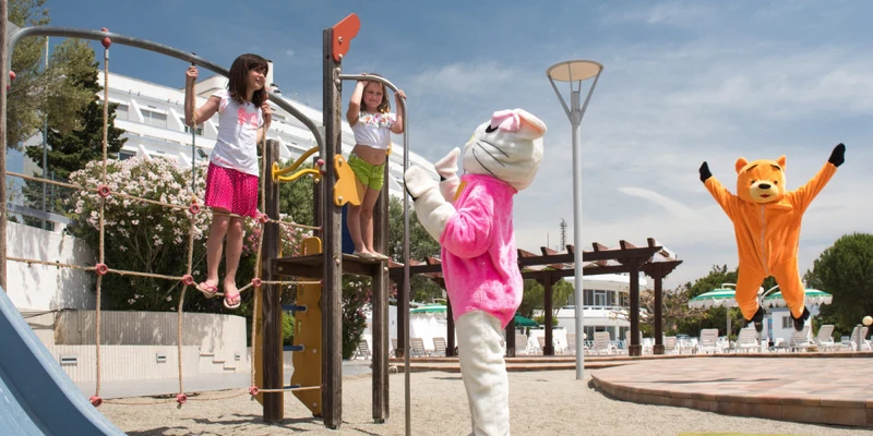 Children climbing playground structure while rabbit and bear mascots interact at Villaggio Club Altalia