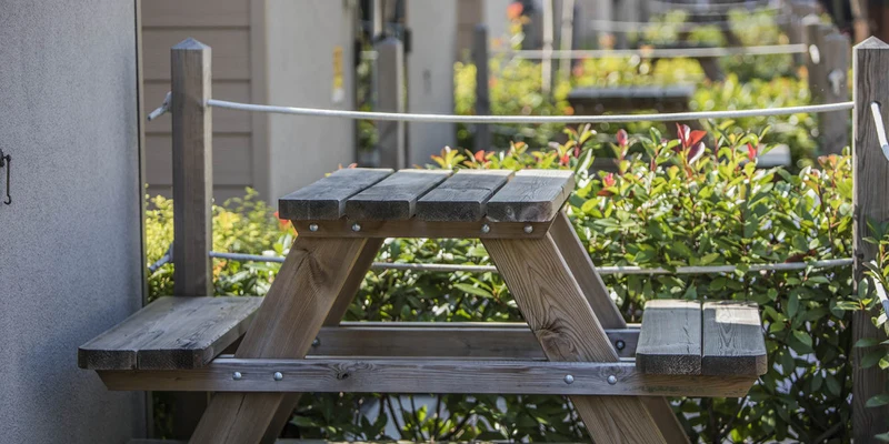 Wooden picnic table placed on a deck, surrounded by greenery and small buildings at hu Venezia Camping in Town
