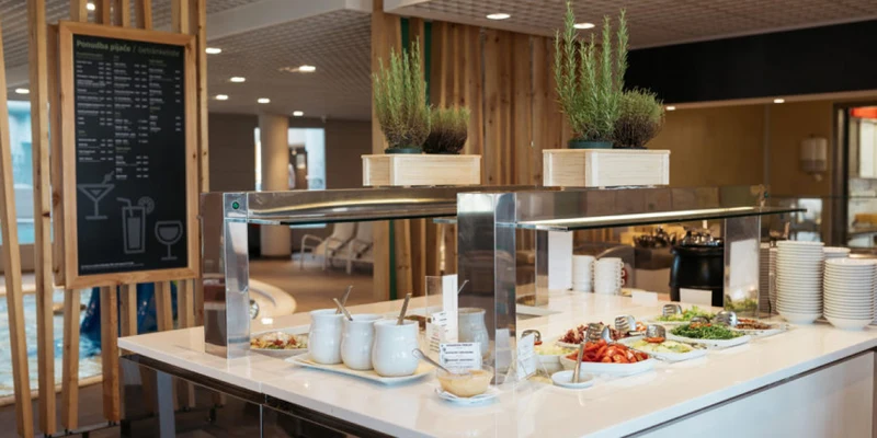 Buffet table displaying various food items, herbs, and condiments, situated in a modern interior dining area at Terme 3000