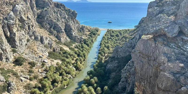 River winding through a rocky canyon towards the ocean, surrounded by greenery at Apollonia