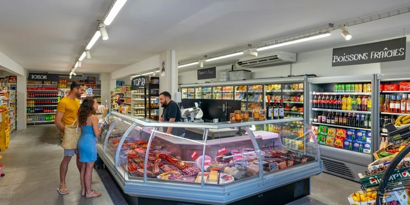 People selecting items at a deli counter in a bright, modern grocery store at Aloha