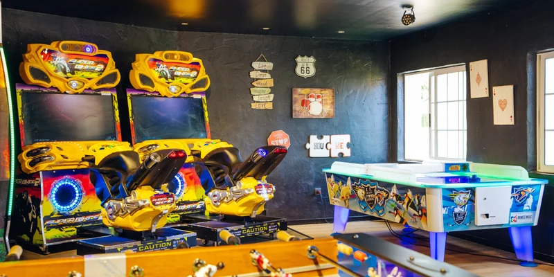 Arcade games and foosball table in a vibrant game room with decorated walls and large windows at Alannia Guardamar