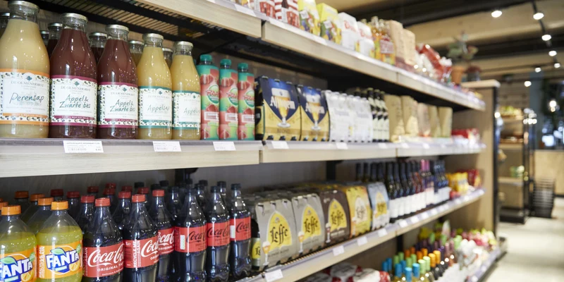 Beverage-filled shelves displaying juices, sodas, and beers in a well-lit grocery store aisle at Park Eksel