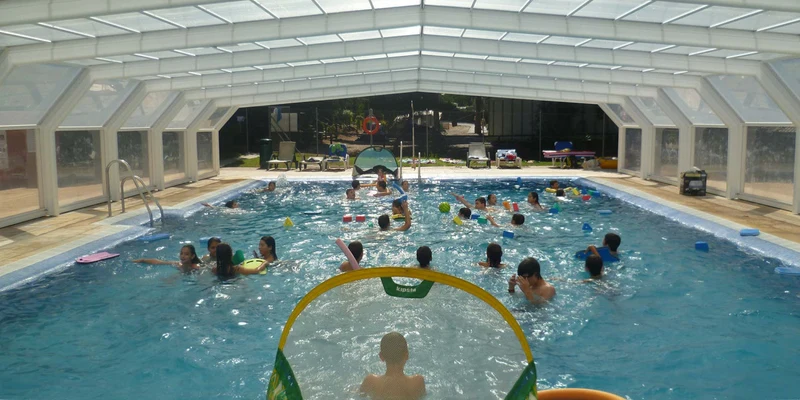 Children swimming and playing in a covered pool, surrounded by pool noodles and toys at Cabopino